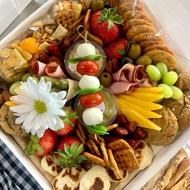 Bramble & Brie Charcuterie Co.'s Picnic Box including various meats and cheeses, olives, house made beer cheese spread and their signature salted espresso chocolate chip cookies