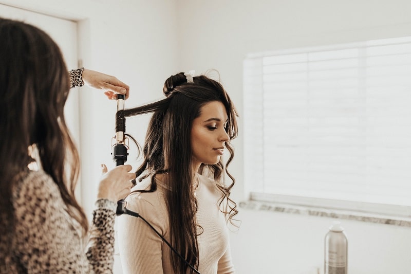 The Day Wedding Owner/Hairstylist Brandi Kwesell curling hair for a bride
