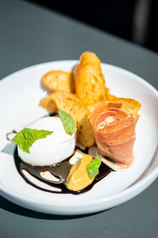 Colorado Craft Social Burrata with basil, pomegranate balsamic reduction, confit garlic and crostinis