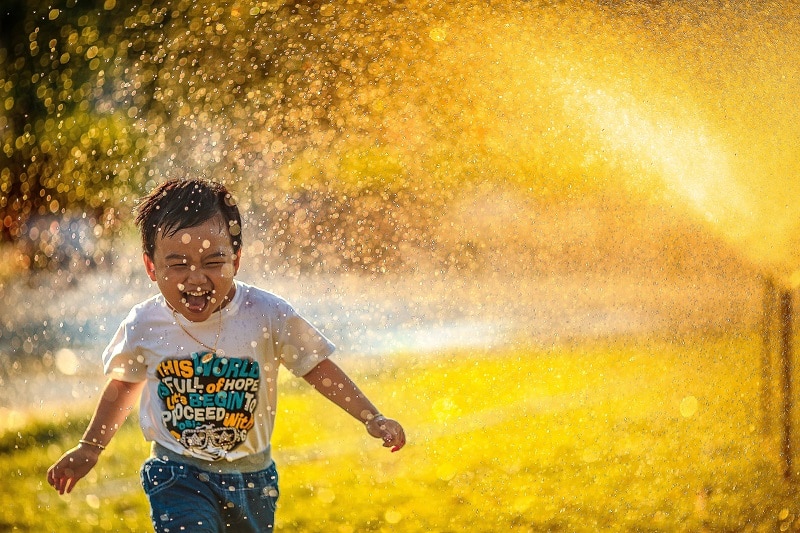 Summer Learning Kid Playing in Sprinkler