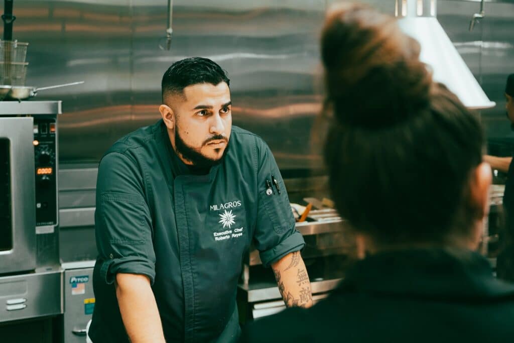 Milagros Executive Chef Roberto Reyes listening to a staff member in the kitchen