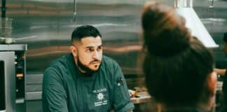 Executive Chef Roberto Reyes listening to a staff member in the kitchen